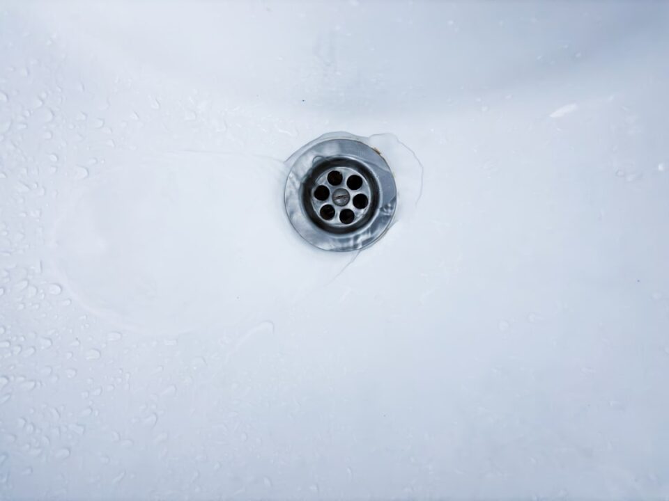 Drain cleaning tips cover illustration with a tidy kitchen sink, bathroom drain, laundry tray, and simple maintenance icons